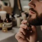 Man applying beard oil in front of bathroom mirror